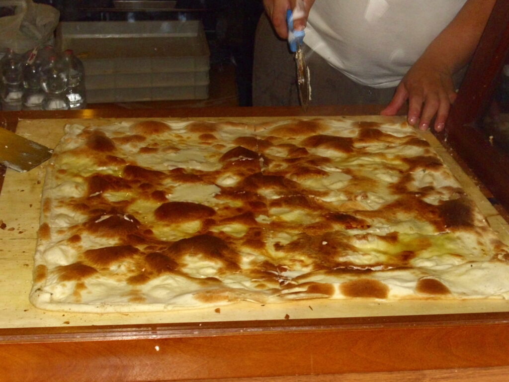 Focaccia di Recco with cheese fresh from the oven on the work table of an artisanal bakery