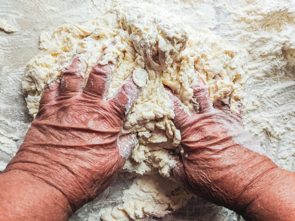 Mani del fornaio che preparano l'impasto della focaccia con i caratteristici buchi