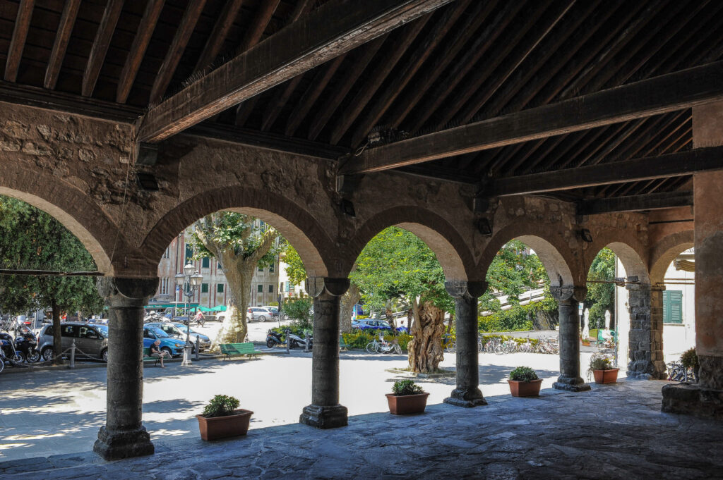 The arches of Levanto's medieval loggia framing the sunlit piazza