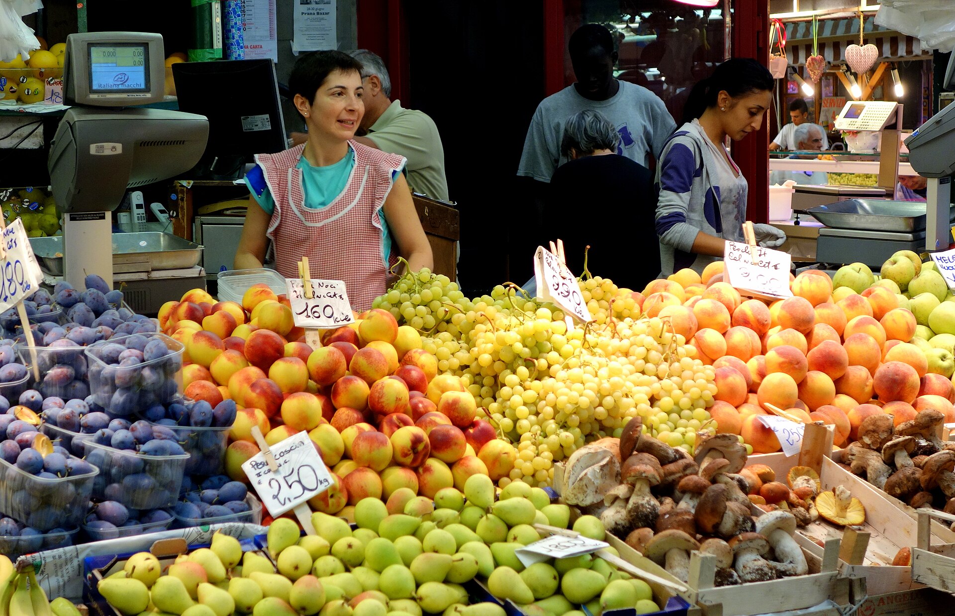 Banco della frutta al Mercato Orientale di Genova con pesche, uva, prugne e funghi porcini