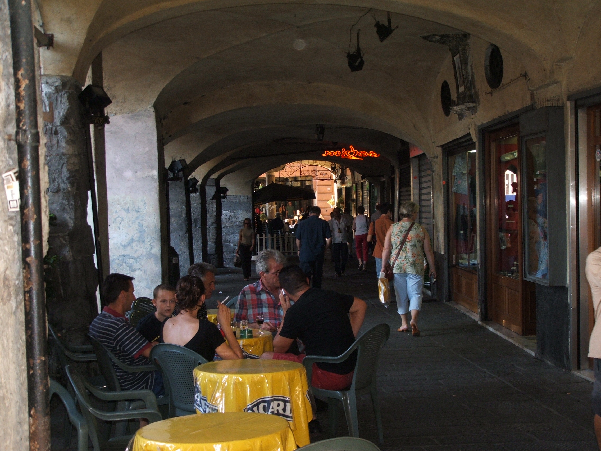Sottoripa arcades in Genoa with tables, people and historic shops