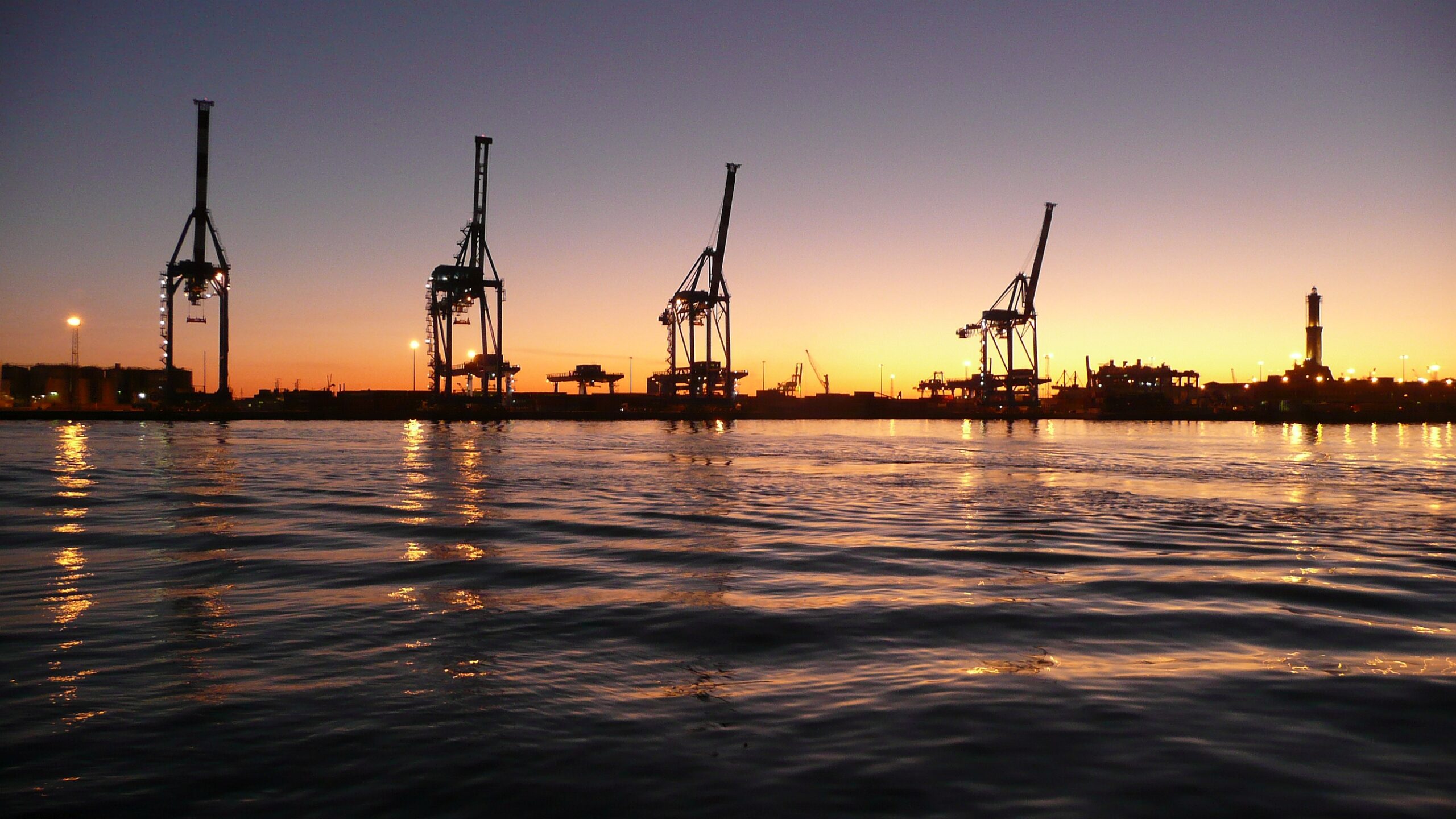 Gru del porto di Genova al tramonto con la Lanterna sullo sfondo