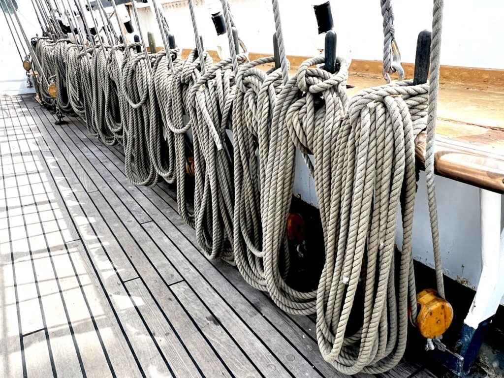 The deck of the Amerigo Vespucci with ropes, rigging and sailors in white uniform