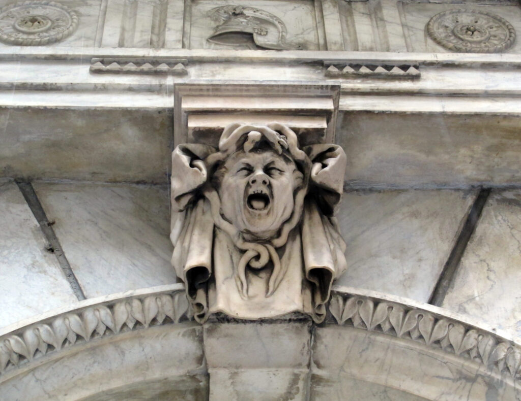 Mascherone apotropaico con volto urlante tra serpenti su un palazzo del centro storico di Genova