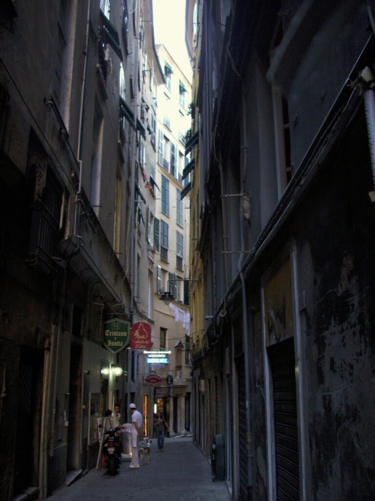 Vicolo del Fieno, a narrow alleyway in Genoa's historic centre with antique signs and tall buildings