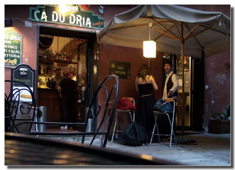 Antica osteria nei caruggi di Genova con tavoli all'aperto e lanterna accesa