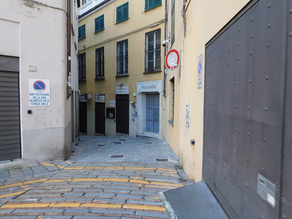 Medieval alley in the historic center of Genoa with dark stone arches
