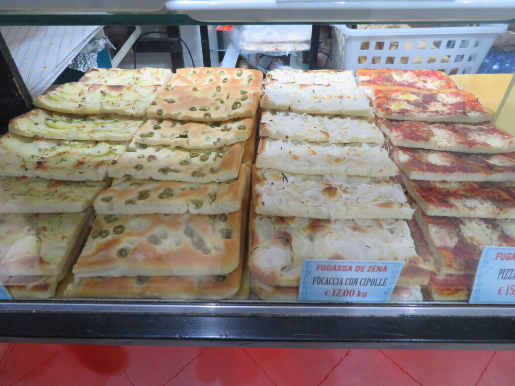 Vassoi di focaccia genovese esposti nella vetrina di una panetteria
