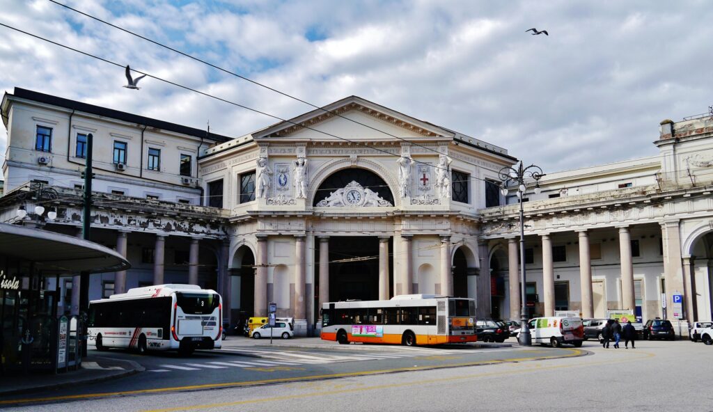 La facciata neoclassica della stazione di Genova Piazza Principe con gli autobus AMT in piazza Acquaverde