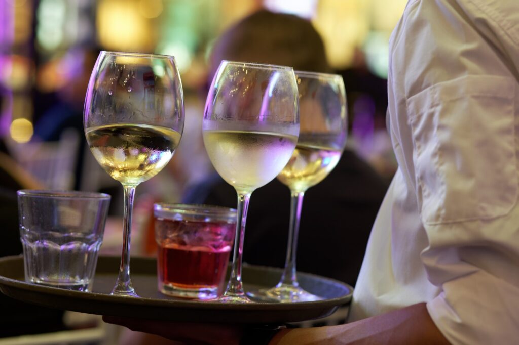Vassoio con calici di vino bianco serviti in un locale alla sera