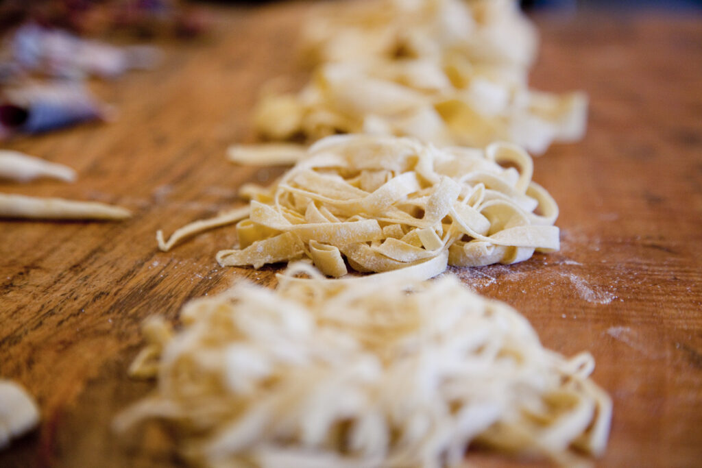 Nests of fresh egg pasta cut by hand on a floured table